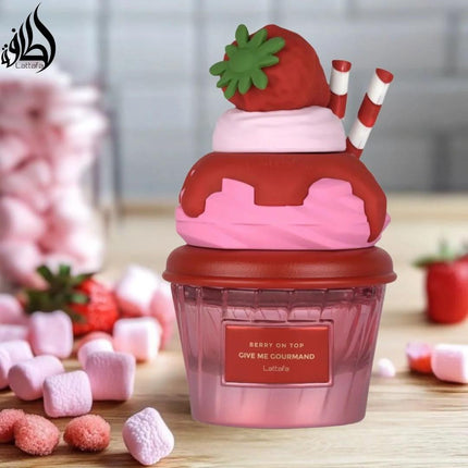 Strawberry-themed cupcake-shaped container with pink frosting and red base on a wooden surface.