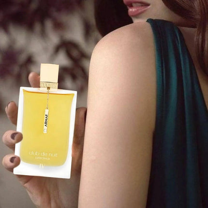 Person holding a yellow perfume bottle with a blurred background