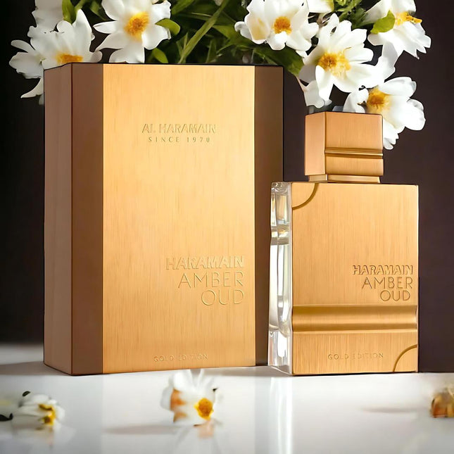 Gold 'Al Haramain Amber Oud' perfume bottle and packaging with flowers in the background
