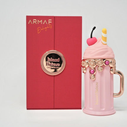 Pink milkshake-shaped perfume bottle with decorative elements in front of an Armaf box.